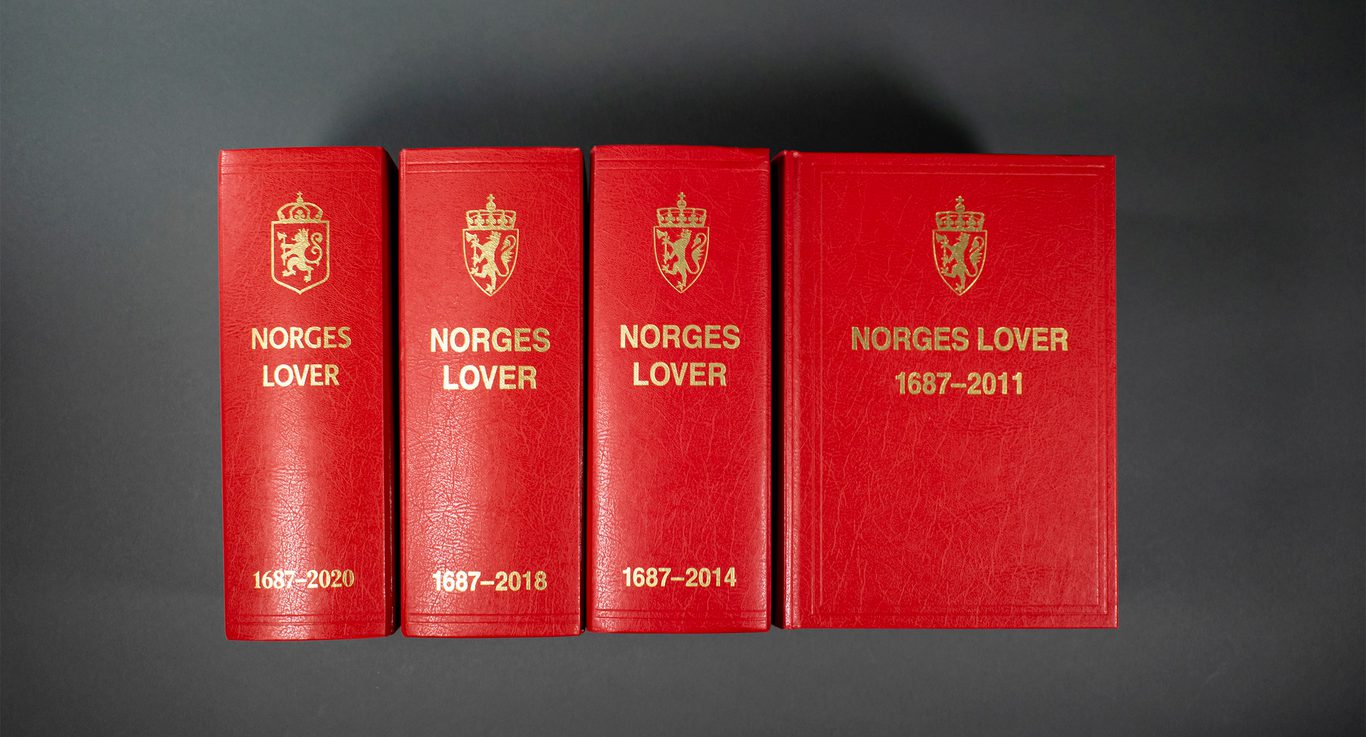 Bildet viser fire versjoner av Norges lover. Vi ser ryggen på tre av dem, og forsiden på den siste versjonen. På omslaget er et et emblem og tittelen "Norges lover" etterfulgt av årstallene 1687–2011"